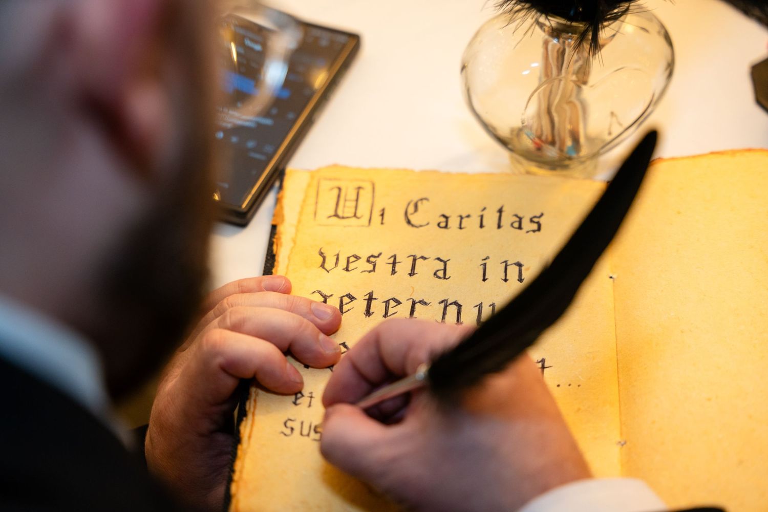 Close-up shot of someone writing calligraphy on yellow paper.