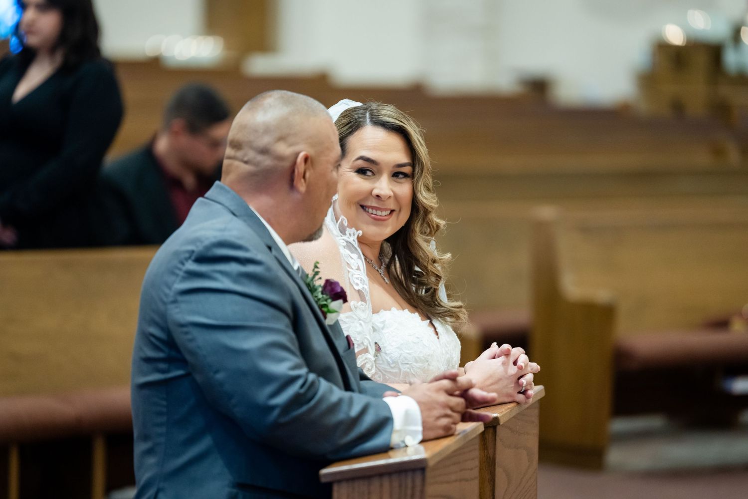 Tender moment shared between couple during wedding ceremony in church pews.