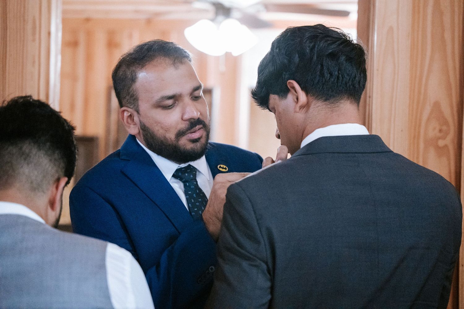 Wedding party members in formal suits sharing a pre-ceremony moment.