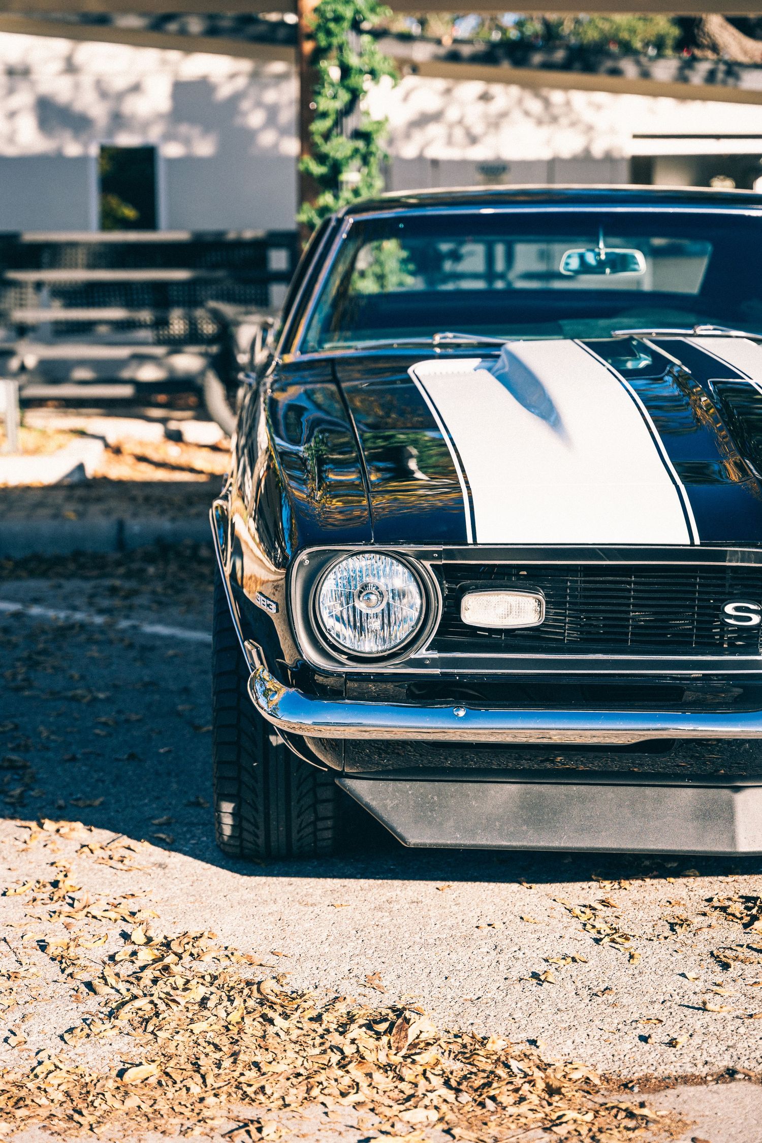 Classic Chevrolet Camaro with white racing stripe displayed at a car meet.