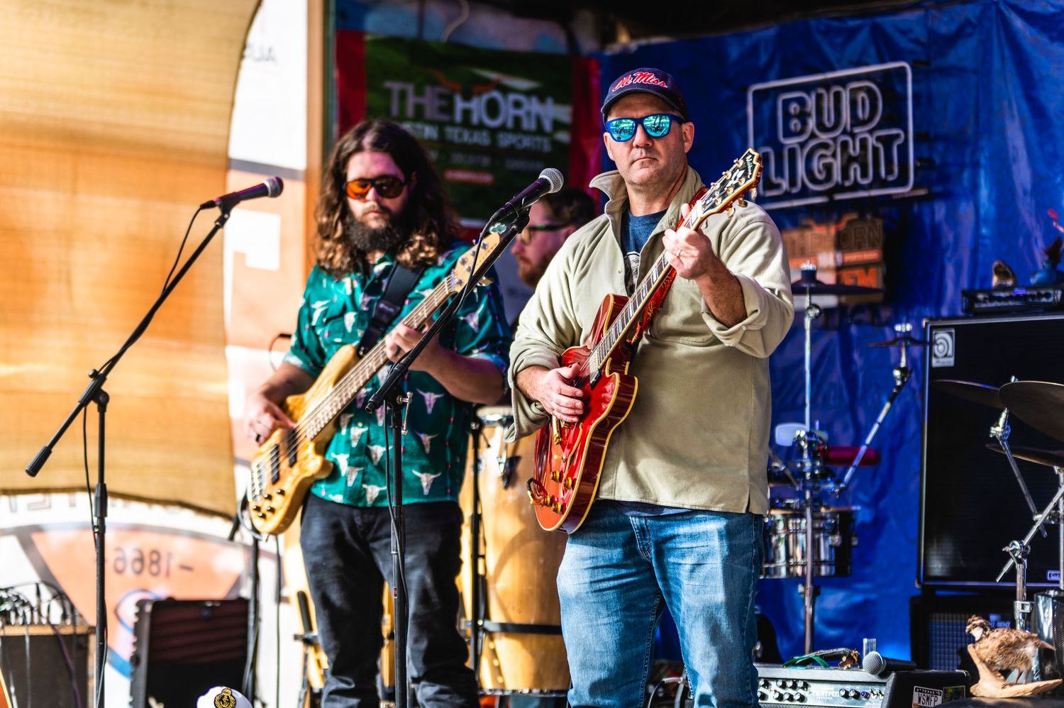 Band performing on outdoor stage with Bud Light banner and multiple instruments.