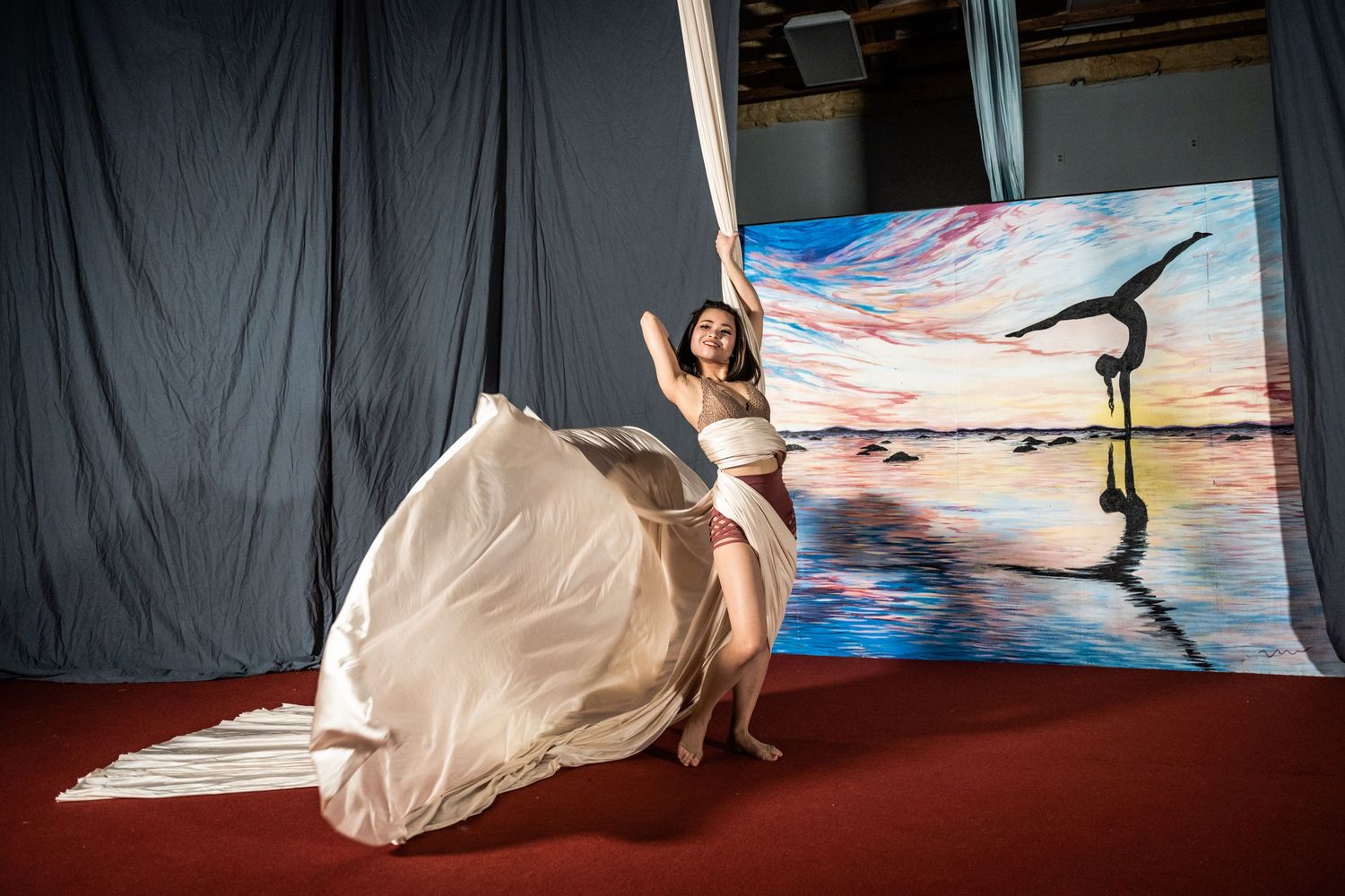 A dancer in a flowing white dress poses gracefully against an artistic backdrop.
