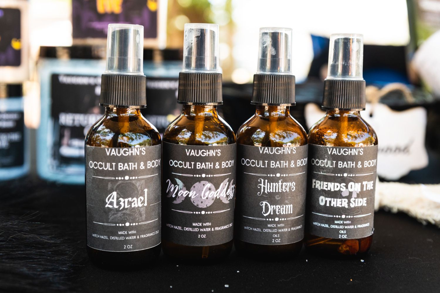 Row of amber glass spray bottles with black labels displayed on dark surface.