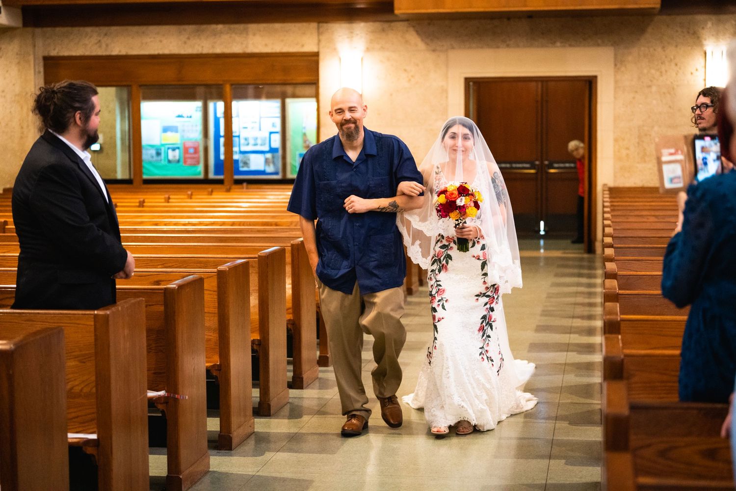 Wedding ceremony taking place inside a church with wooden pews.
