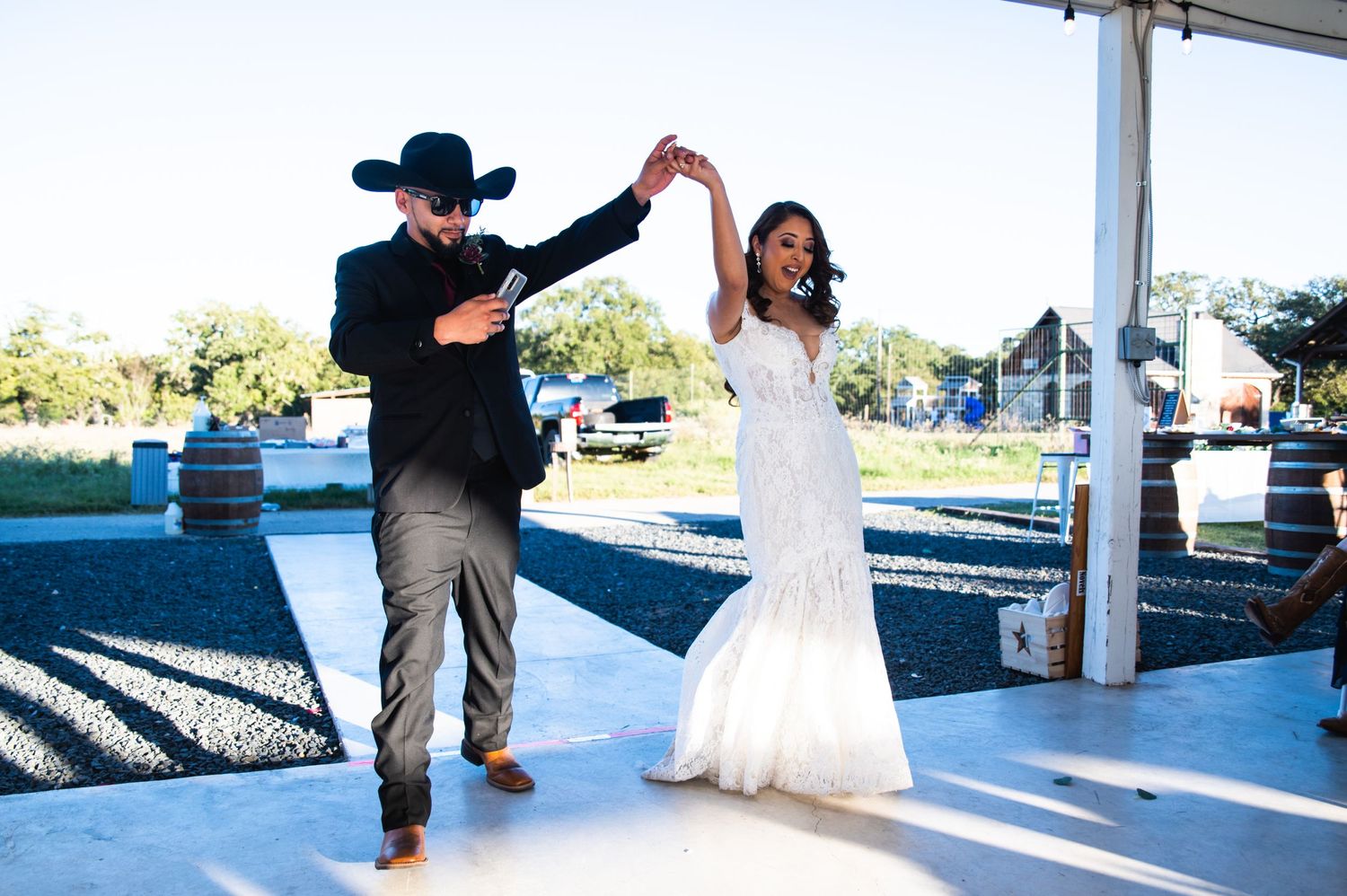 A couple dancing under an outdoor pavilion with the bride wearing a beautiful white mermaid wedding dress.