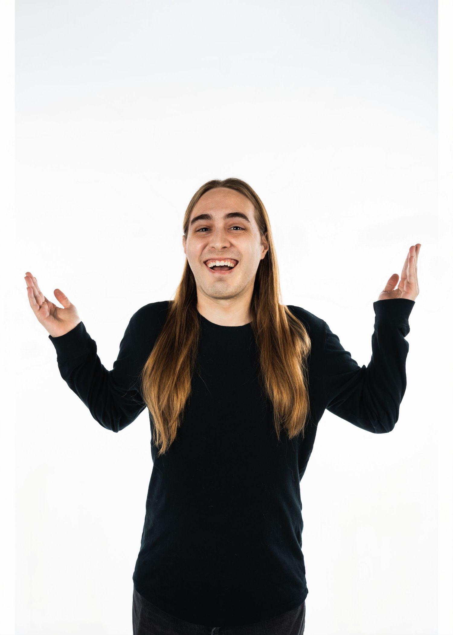 Person in black sweater expressing joy with raised hands against white background.