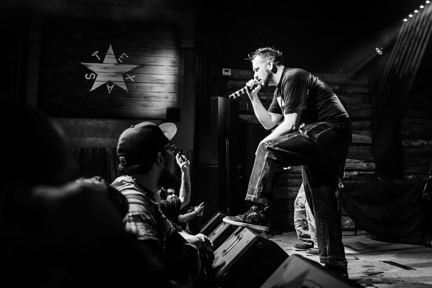 Dramatic black and white shot of performer engaging with crowd during concert.
