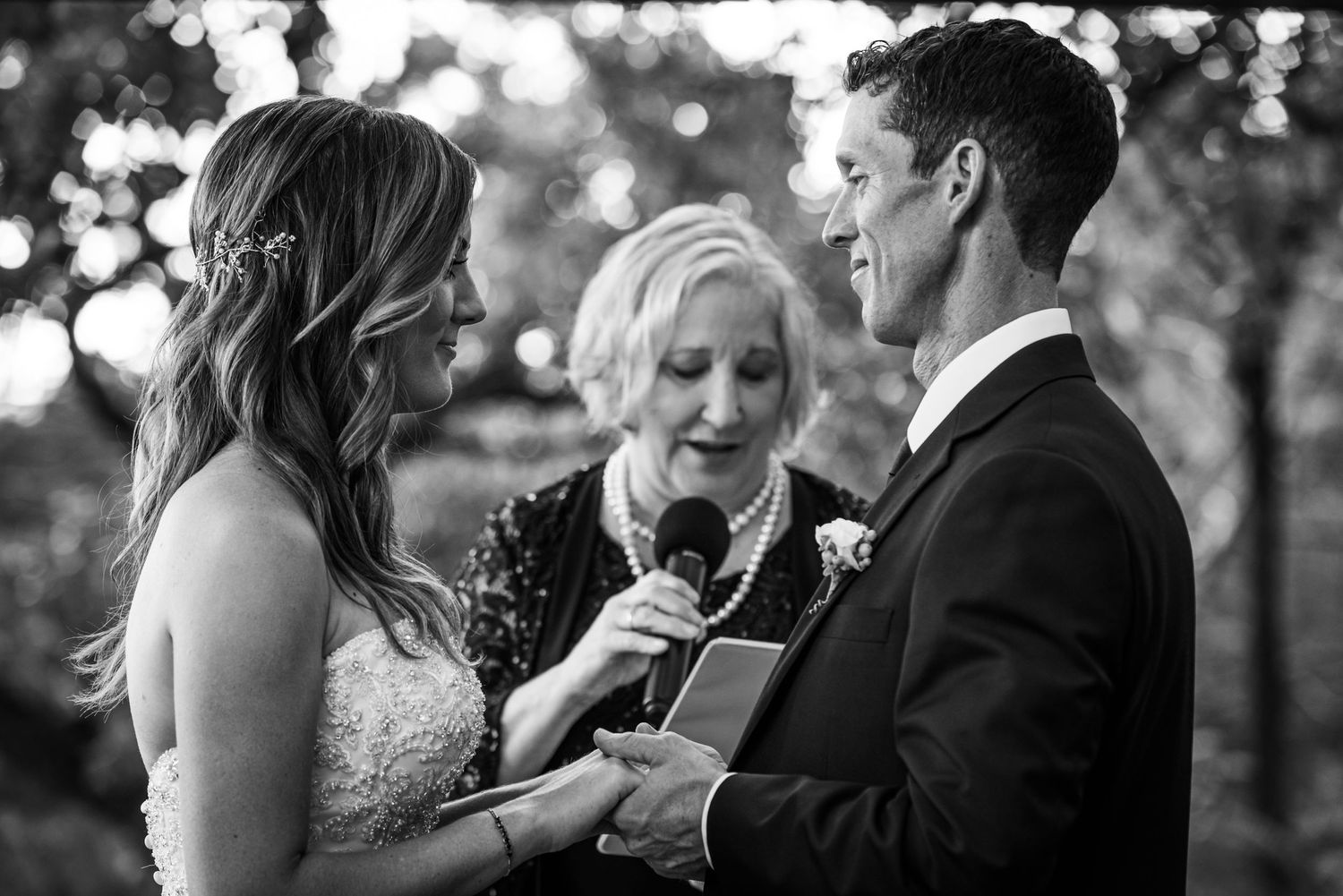 Black and white wedding ceremony photograph during vow exchange.