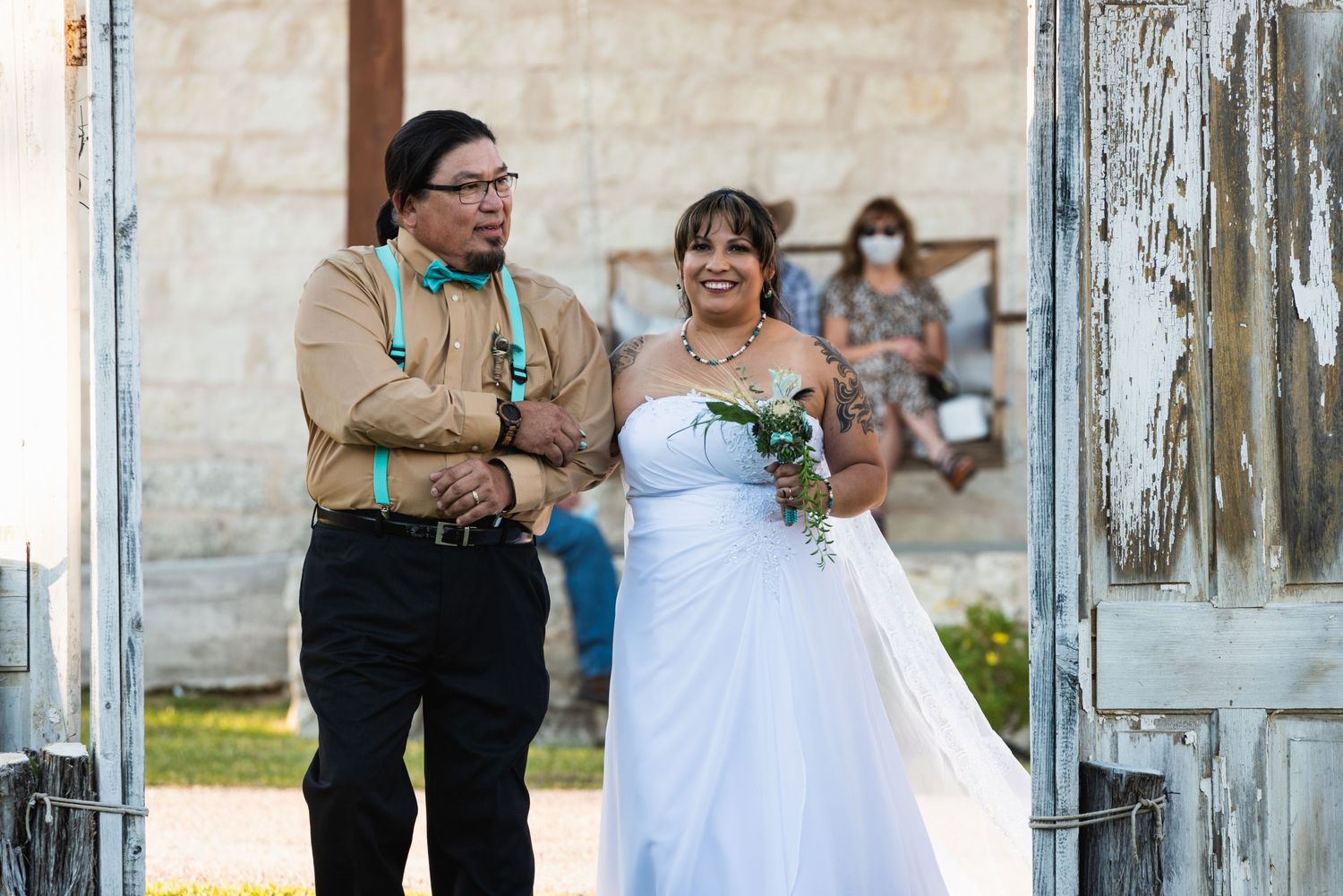 Wedding ceremony processional on rustic outdoor patio with stone walls.