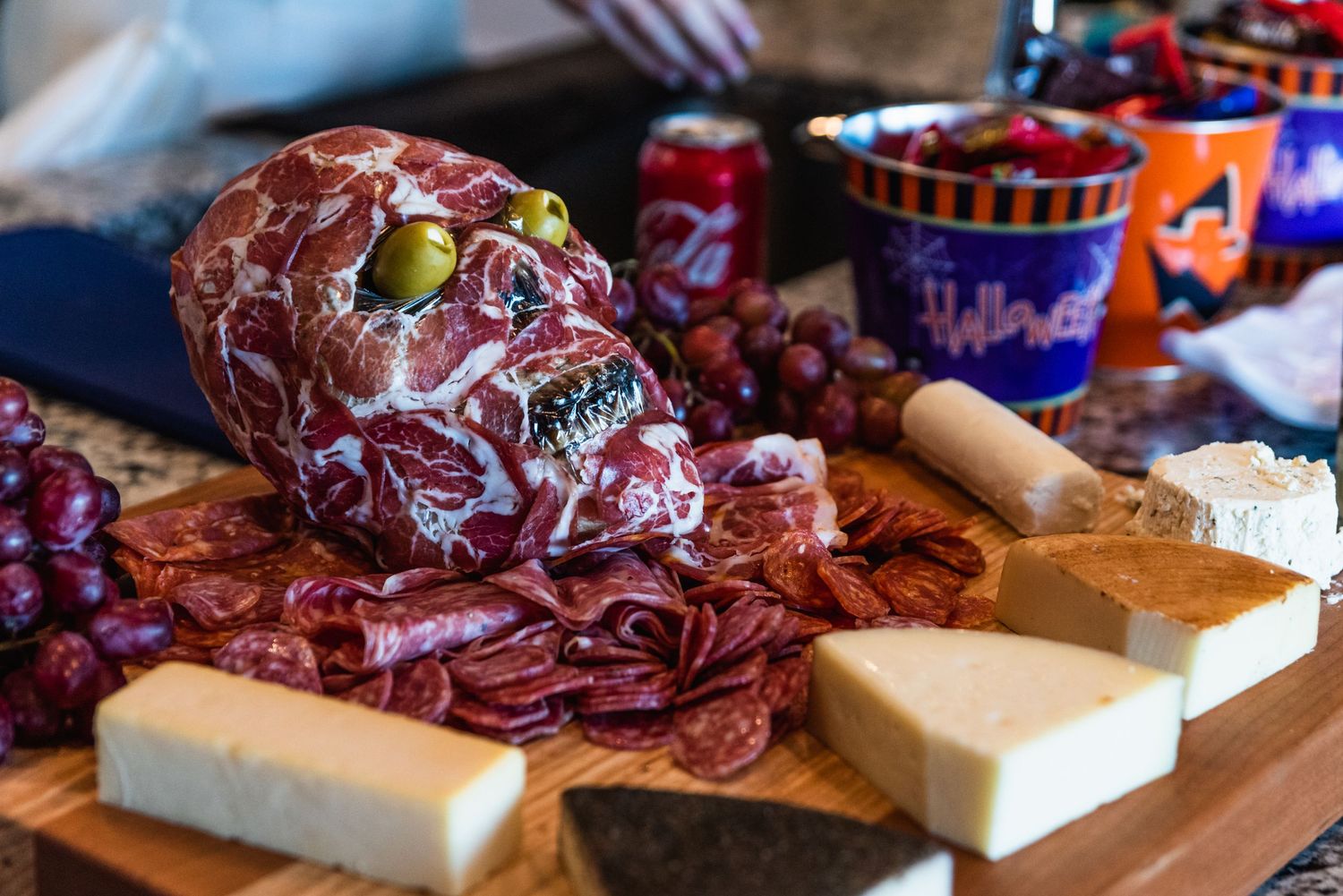 A Halloween-themed meat and cheese board featuring a decorative skull centerpiece.
