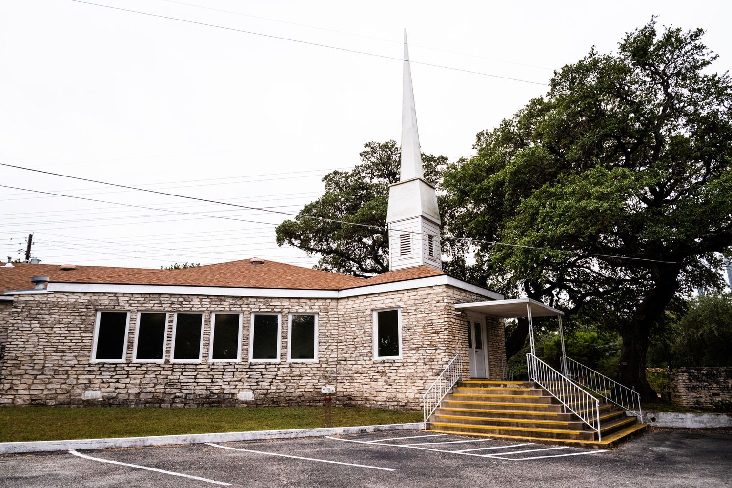 Stone church building with white steeple and arched windows on sunny day.