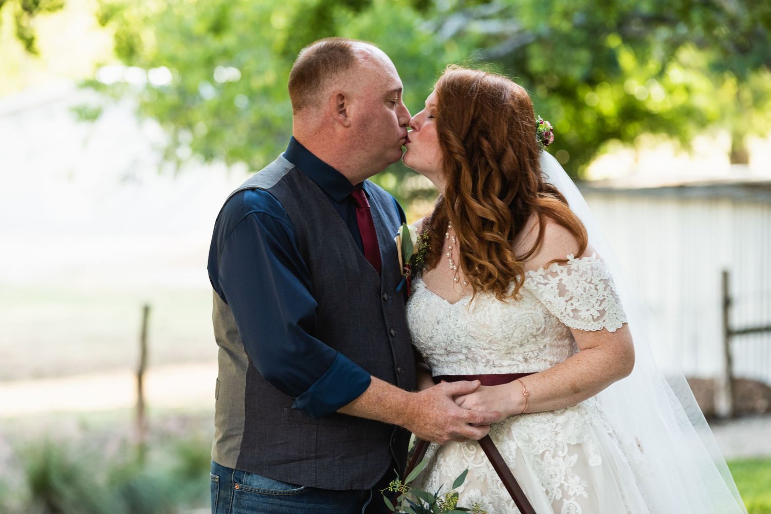 A romantic wedding portrait with sunlight filtering through trees in the background.