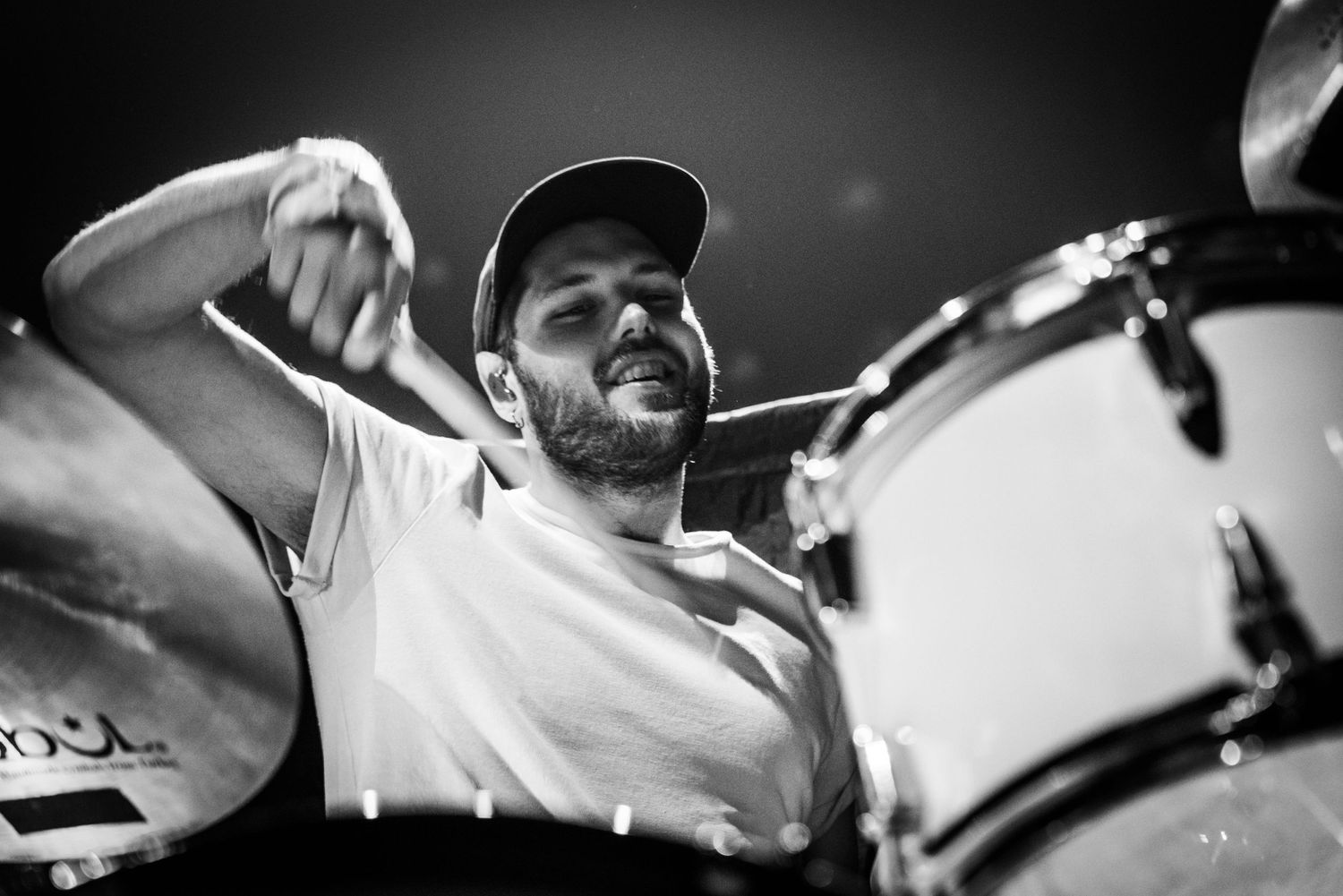 Intense black and white shot of drummer performing on stage.