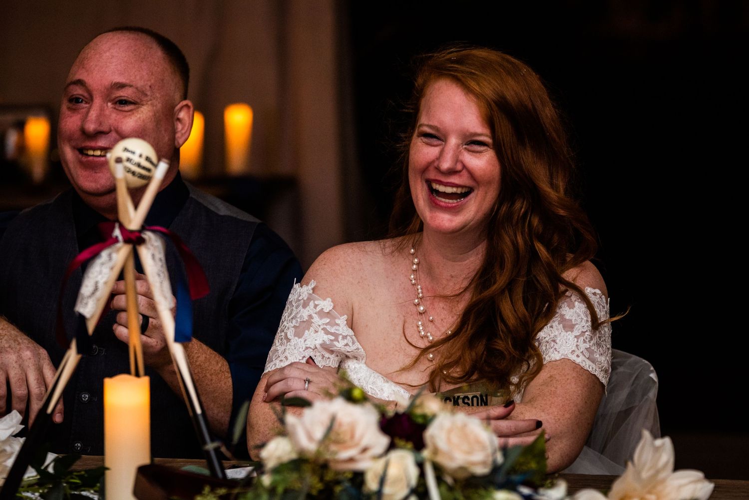 Joyful moment captured at wedding reception dinner with table decorations and candlelight.