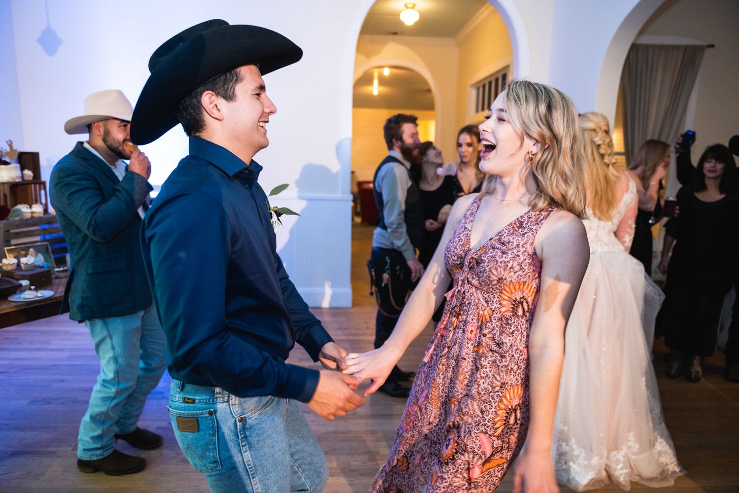 Dancing guests enjoy themselves on the dance floor during a wedding reception in an elegant venue.