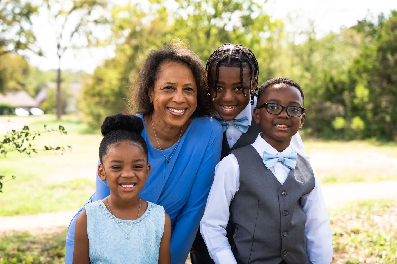 Small family group in coordinated outfits smiling together outdoors.