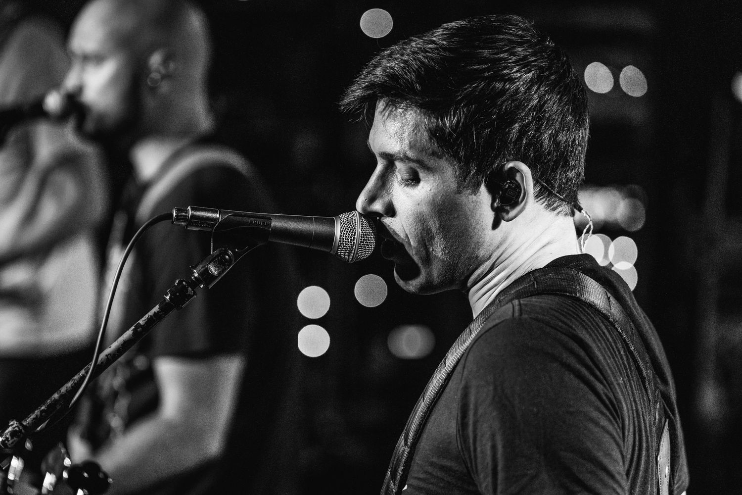 Musician sings passionately into microphone during black and white performance shot.