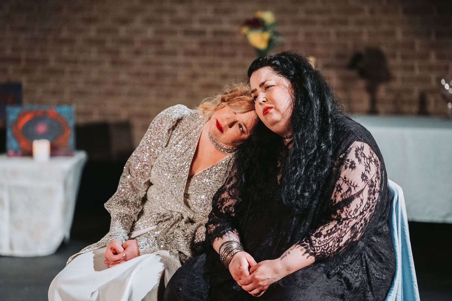 Two performers share an intimate dramatic moment during a stage production.