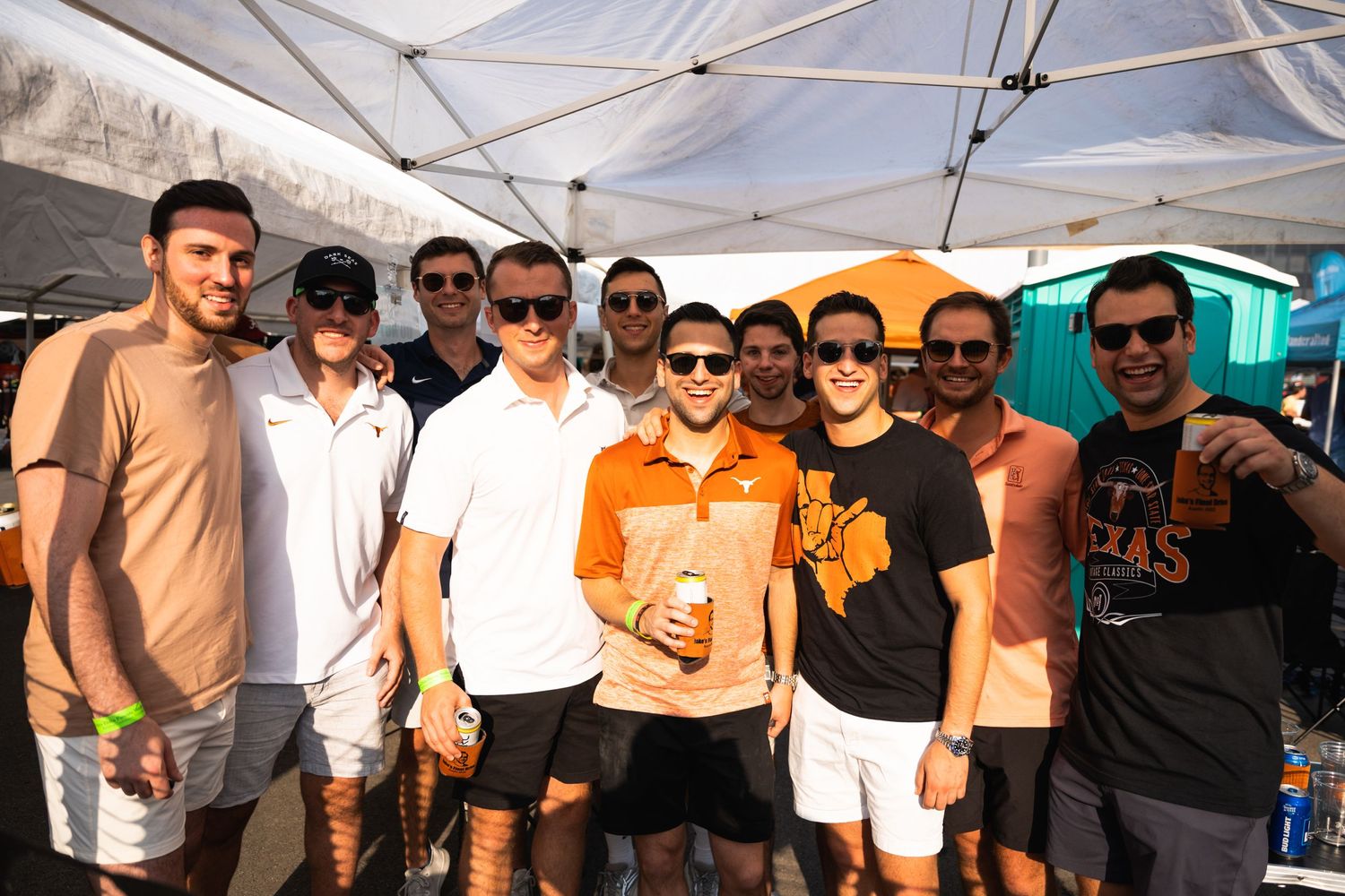Group of friends in casual attire posing together at outdoor summer event.
