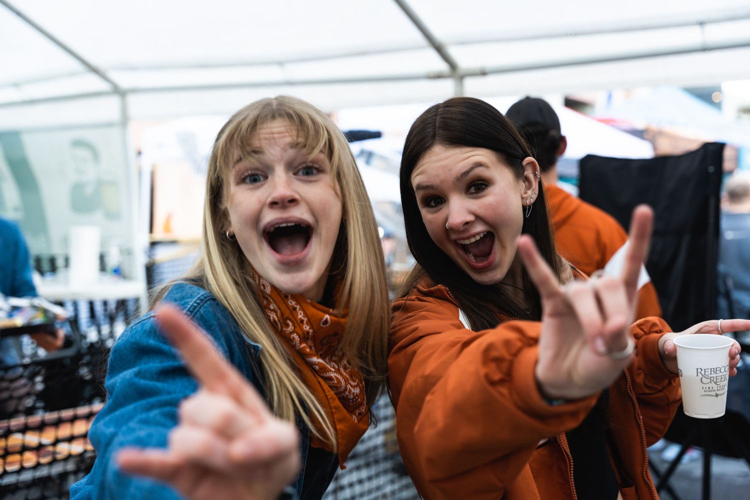 Two friends making excited expressions and gestures at an outdoor event.