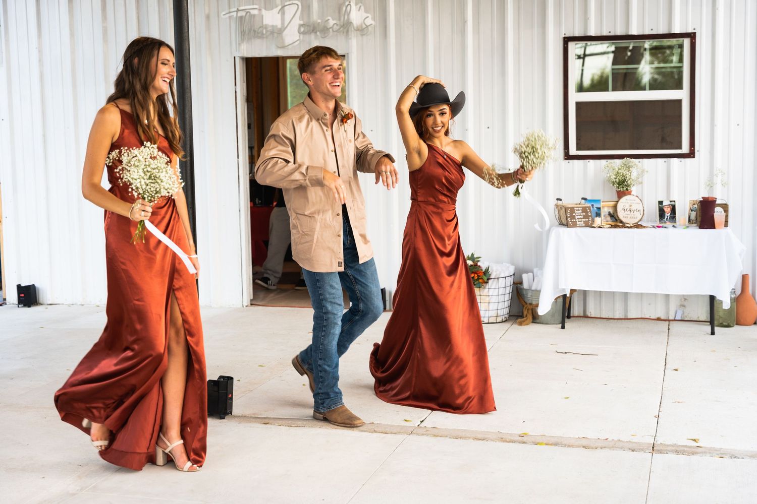 Wedding party members dance and celebrate in formal attire at indoor reception venue.