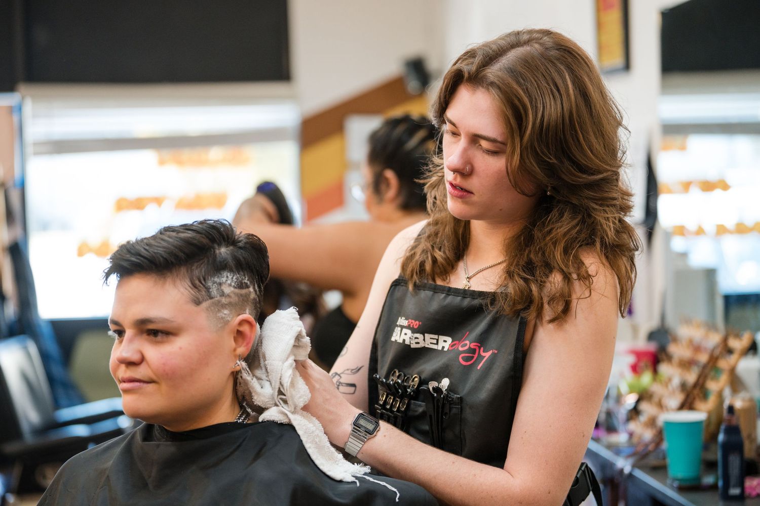 Hairstylists work with clients in a modern salon setting, styling hair and providing professional beauty services.
