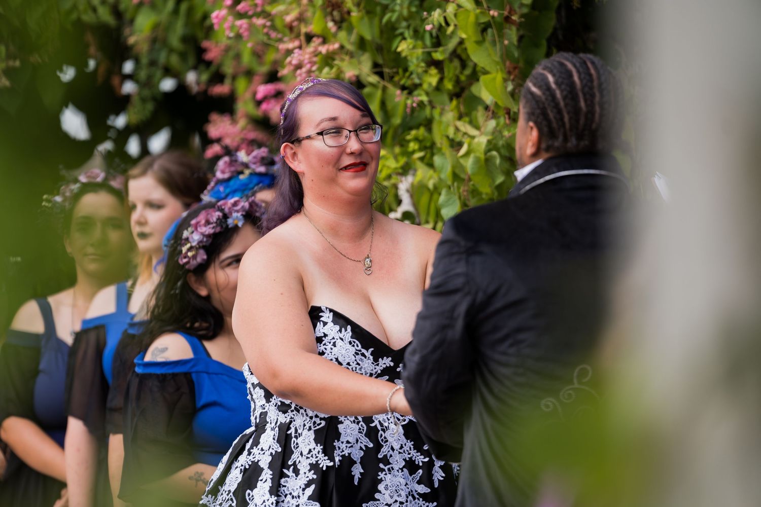 A couple shares a joyful moment together outdoors surrounded by green foliage during a special occasion.