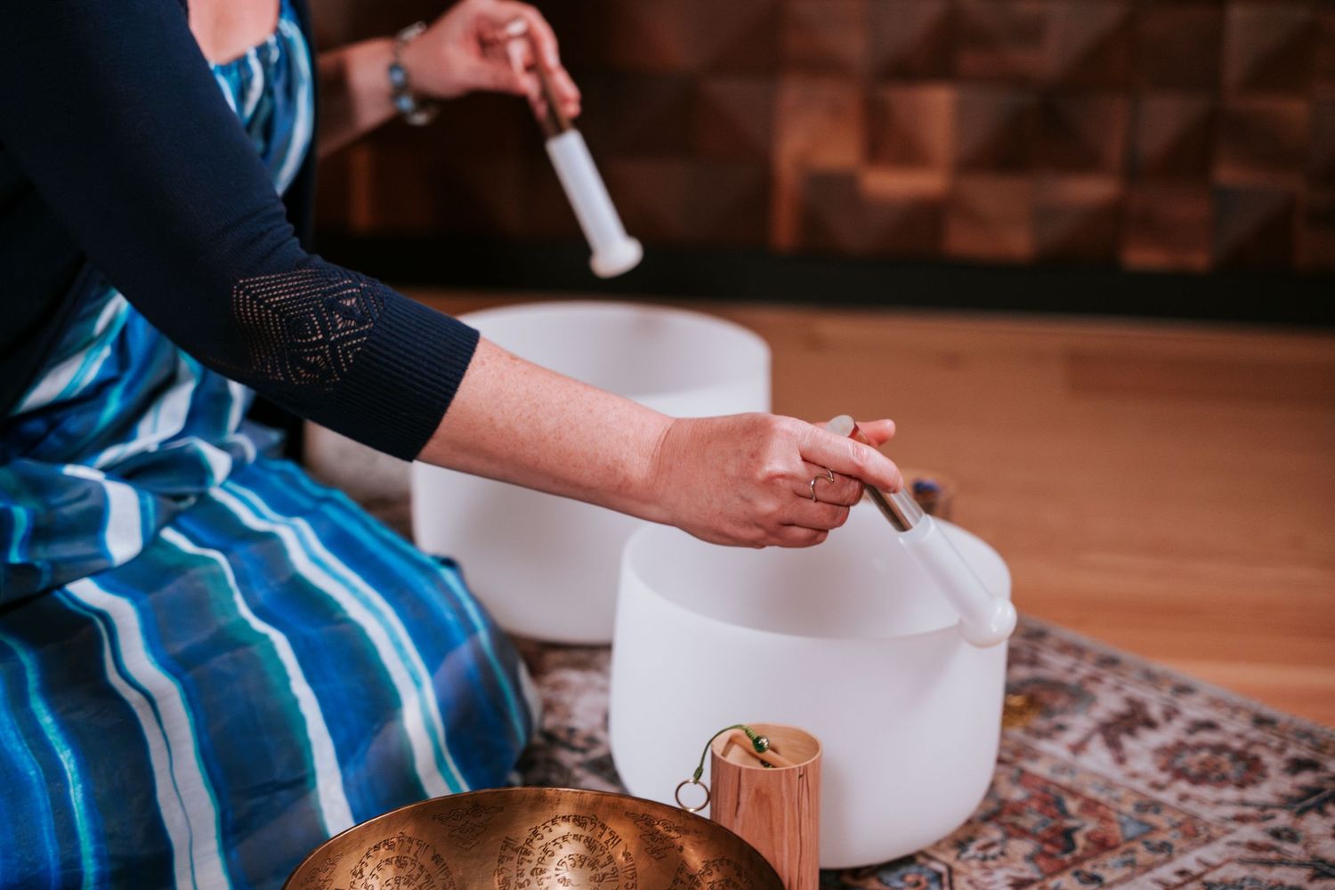 Hands roll out dough on a wooden cutting board covered in flour while preparing homemade pasta.