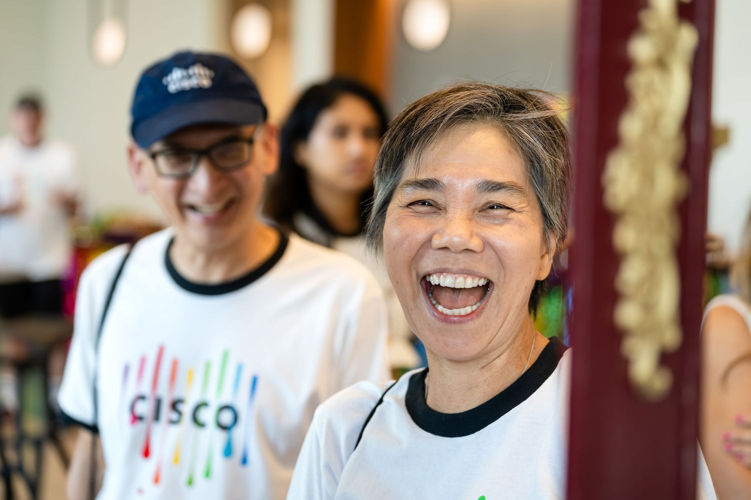 Cisco employees in branded white t-shirts laughing and smiling during a team volunteer event.