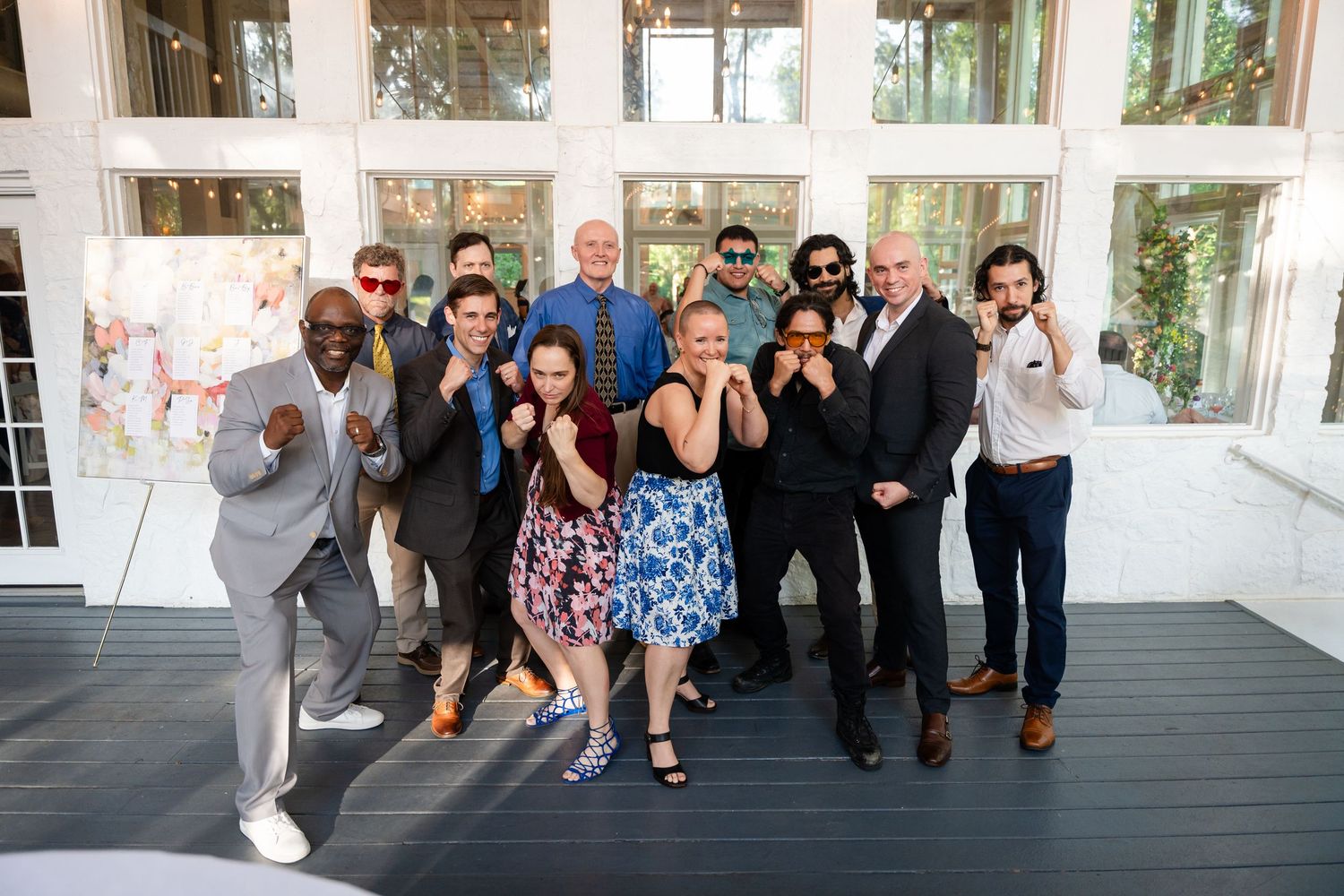 Group of friends posing playfully at an outdoor wedding reception on a wooden deck.
