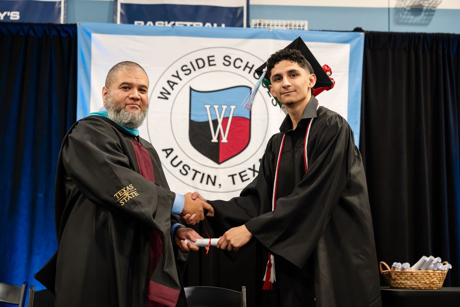 Graduate shaking hands with faculty member at Wayside School Austin Texas graduation ceremony.