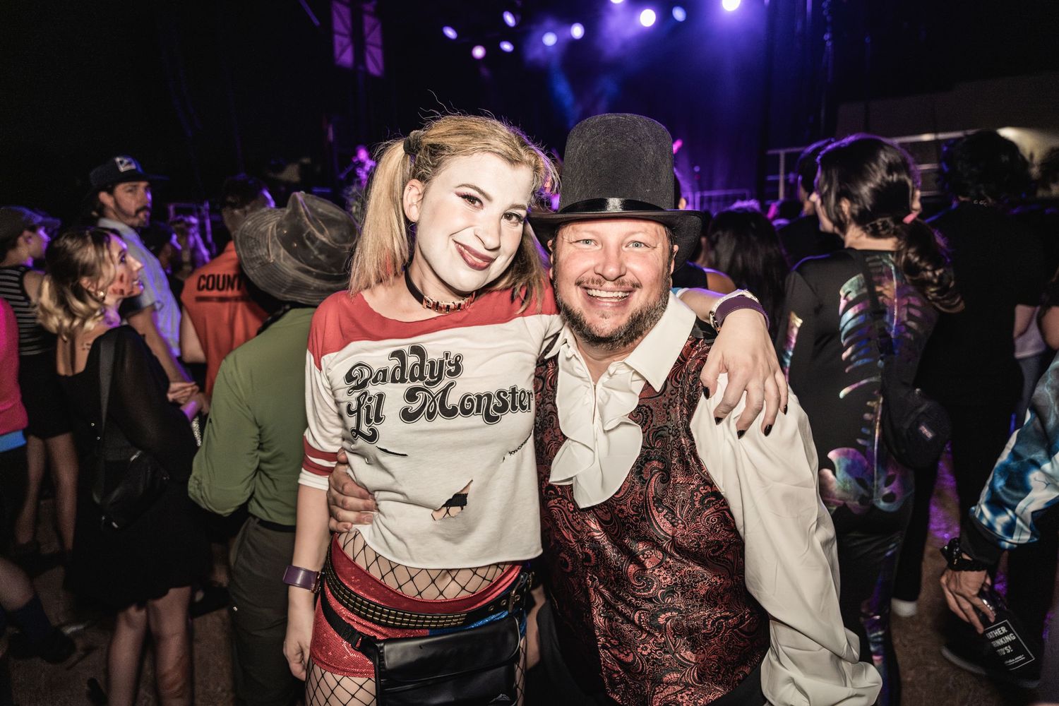 Concert attendees in costume pose at a nighttime music festival event.