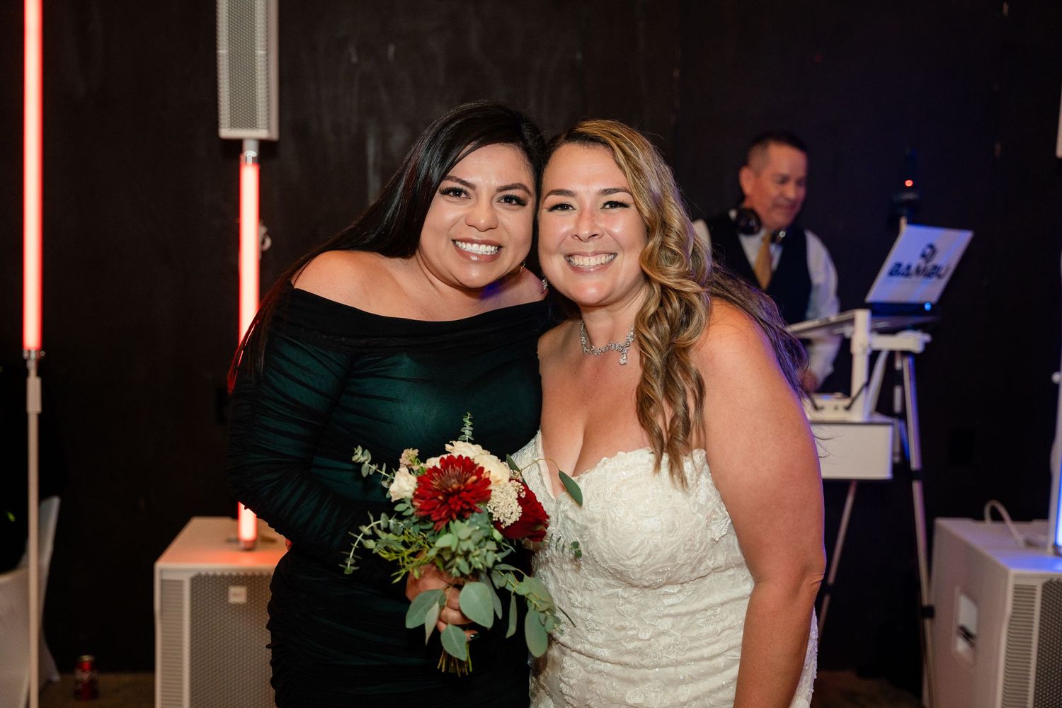 A celebratory moment captured between wedding guests under ambient lighting at the reception.