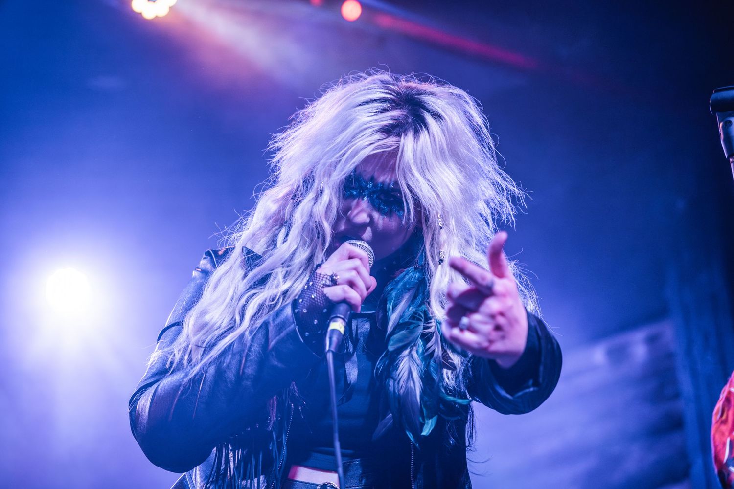 Dramatic concert performance with blue lighting and dynamic stage presence.