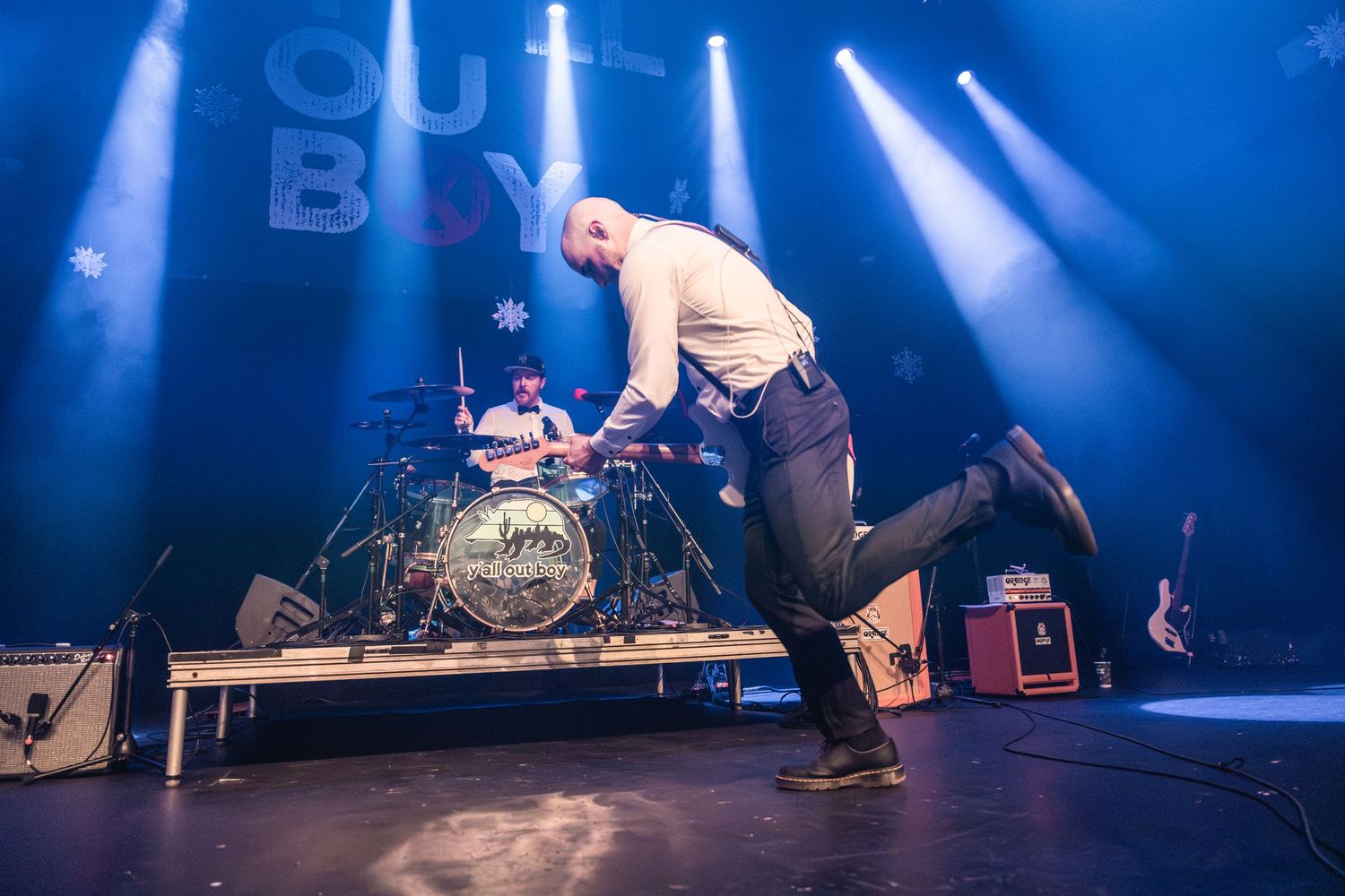 Performer leaping energetically on stage during a live concert with blue lighting.