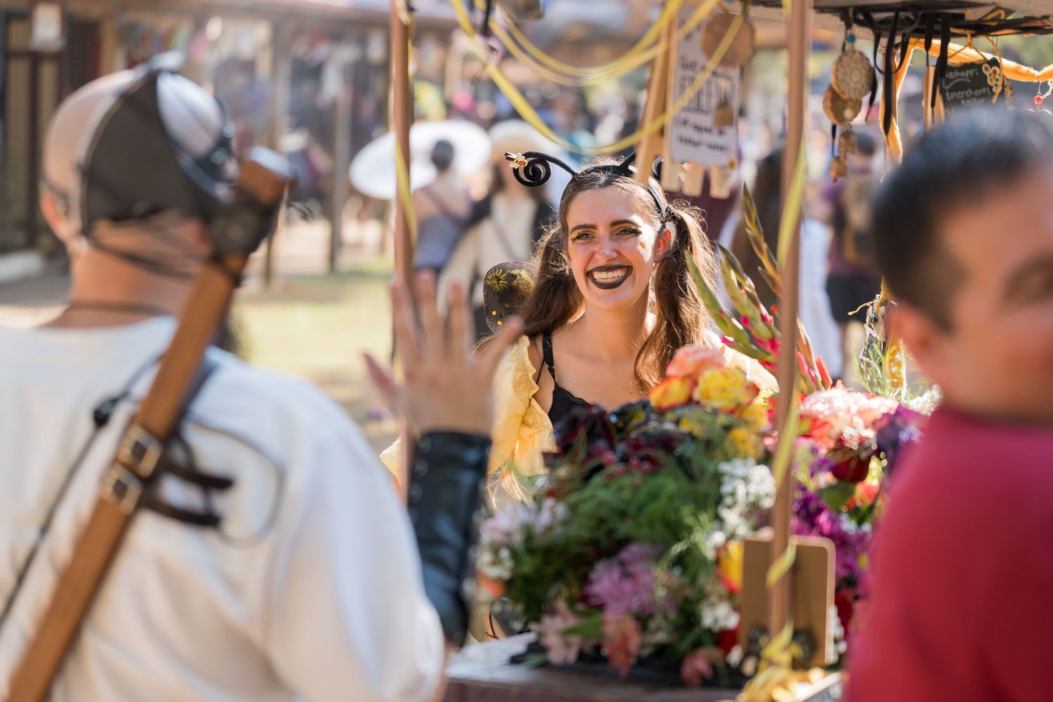 Festival attendee with floral bouquet enjoying the atmosphere at an outdoor market.
