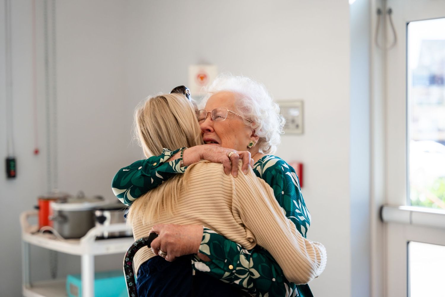 Two people sharing a warm embrace in a bright indoor setting.