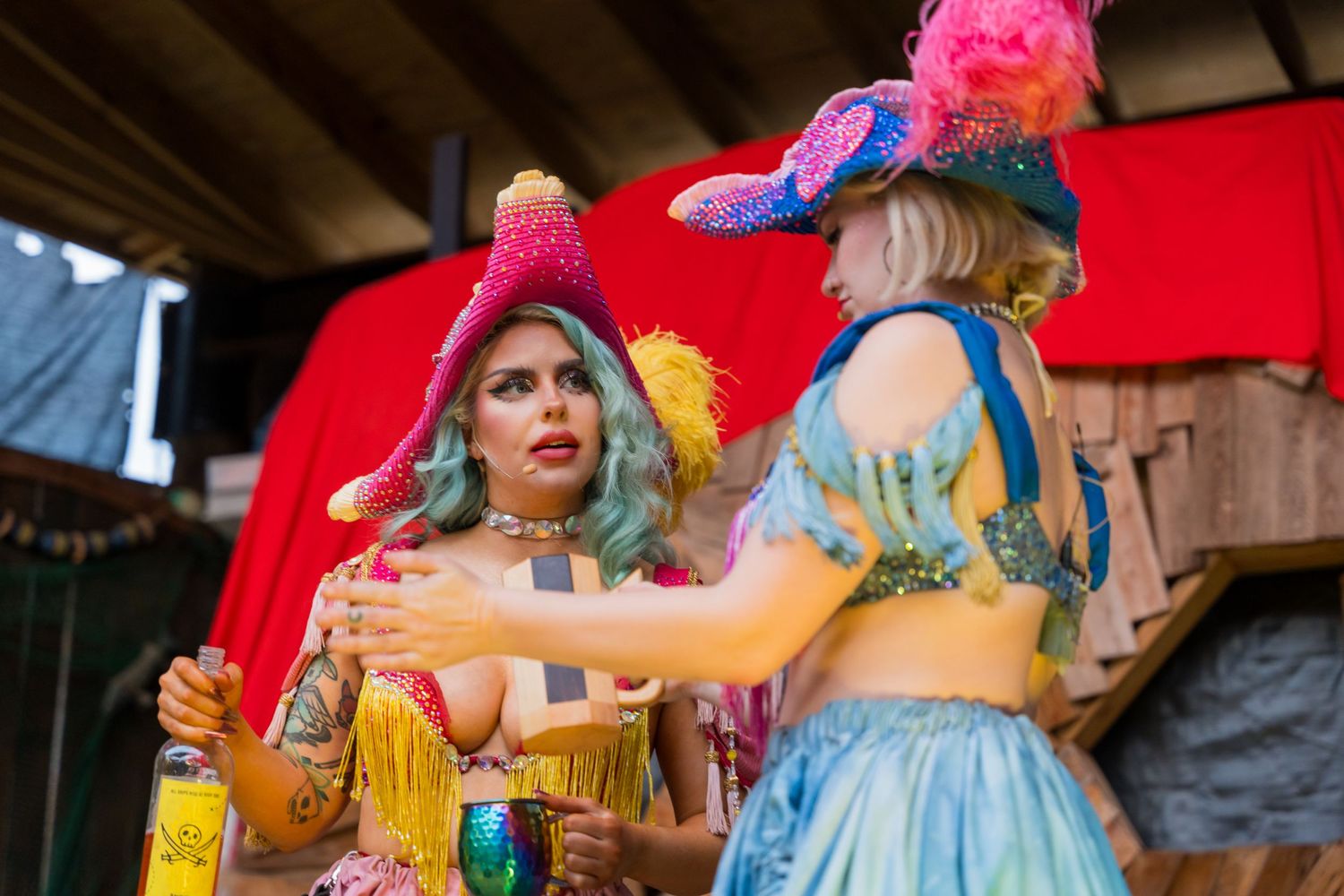 Performers in colorful renaissance costumes entertain on stage at a fair.