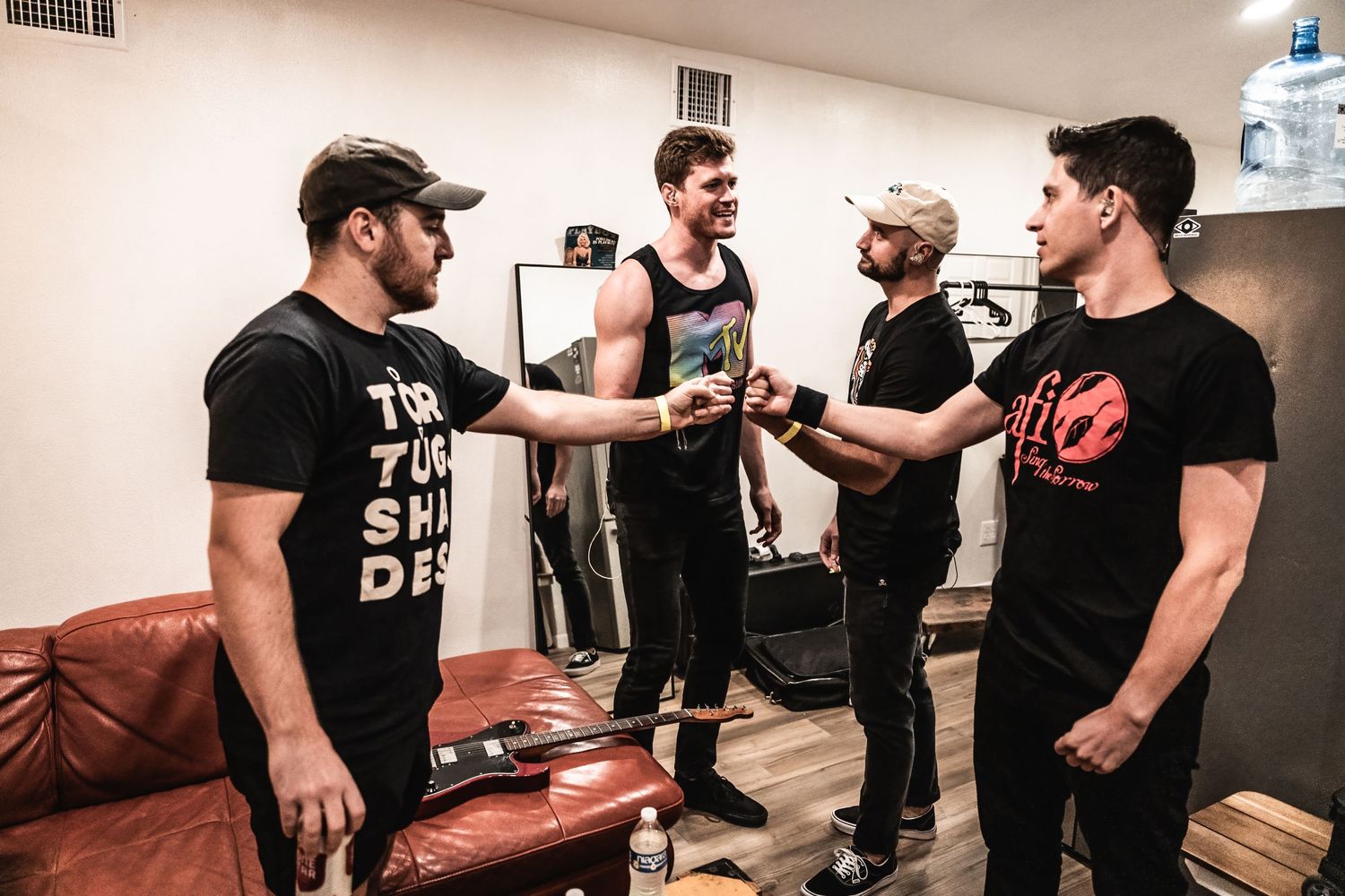 Band members having discussion in rehearsal room with leather couch.