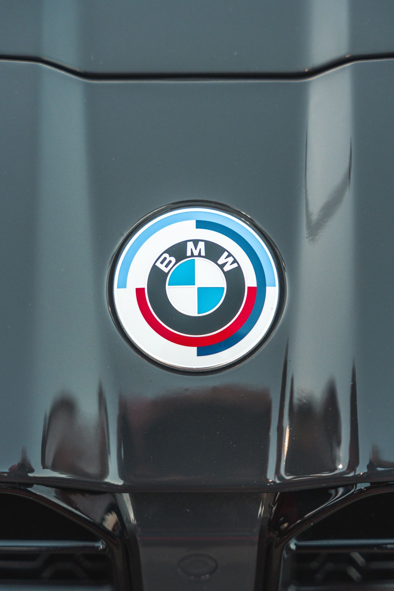 Close-up of BMW M Sport logo badge on grey vehicle hood.