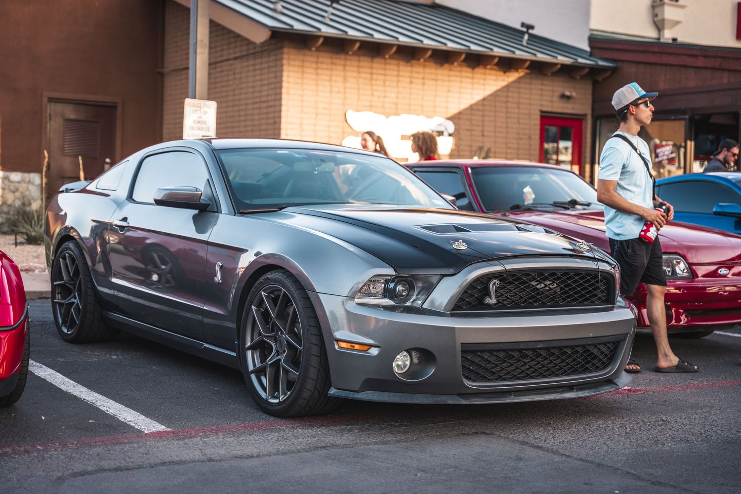 Gray Ford Mustang Shelby GT500 with black wheels parked in a shopping center lot.