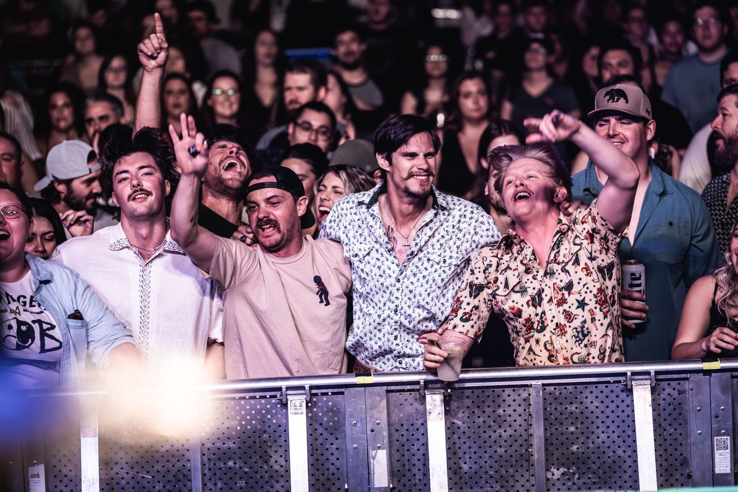 Concert crowd enjoying live music performance with enthusiasm at a venue's front barrier.