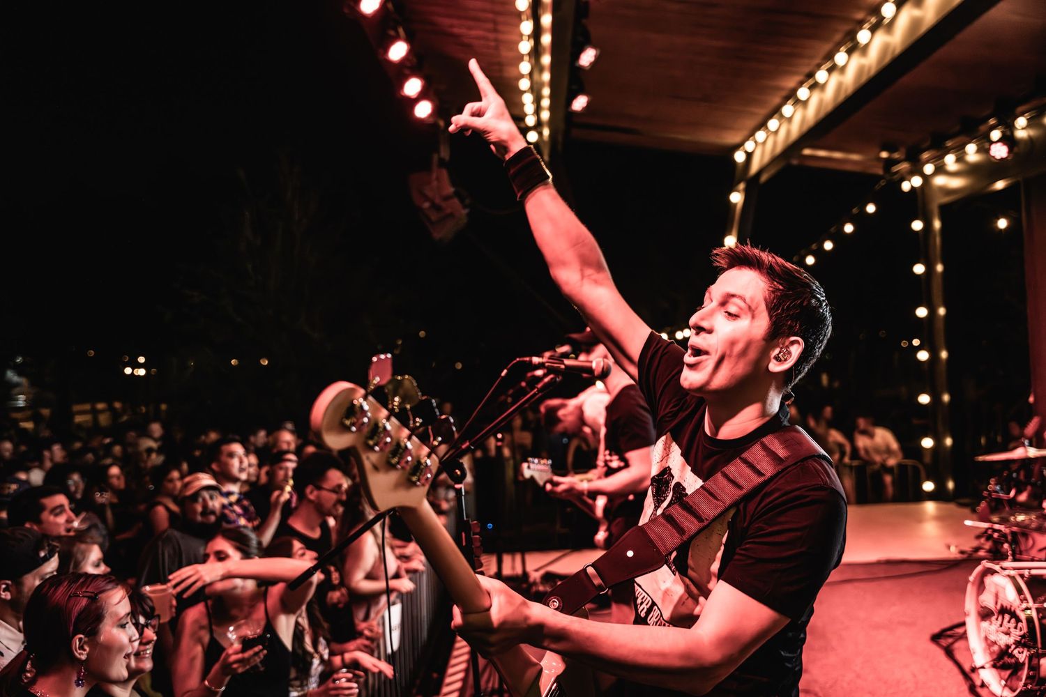A high-energy concert performance in a venue with string lights visible overhead.