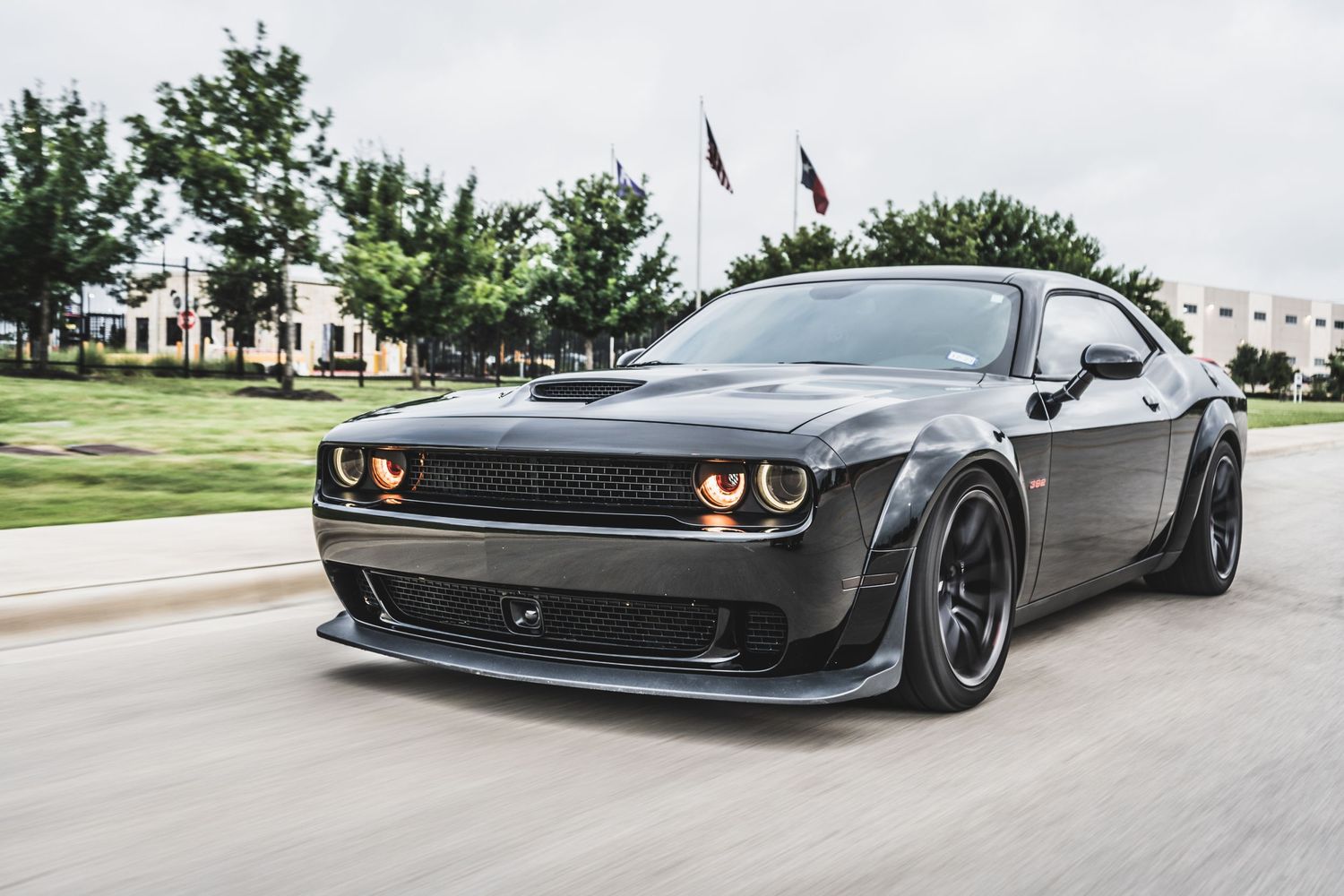 Menacing black Dodge Challenger with wide body kit and sport wheels in motion.