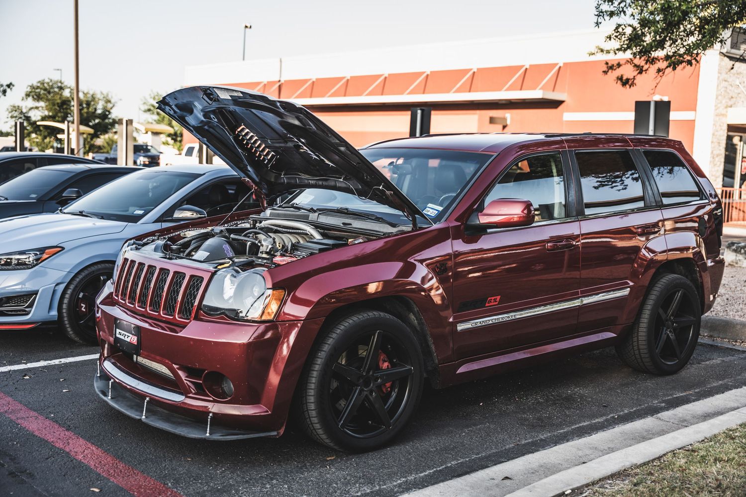 Modified burgundy Jeep Grand Cherokee SRT with hood open displaying engine bay.