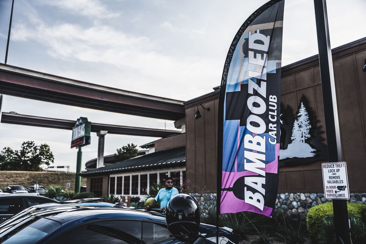 Car dealership exterior with promotional banners and parked vehicles under cloudy sky.