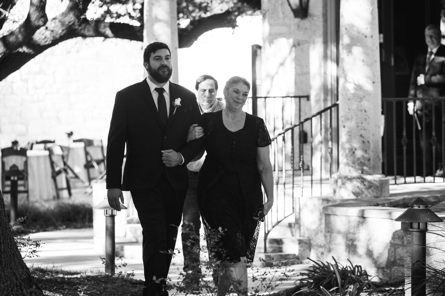 Black and white photo of formal occasion entrance along garden pathway.