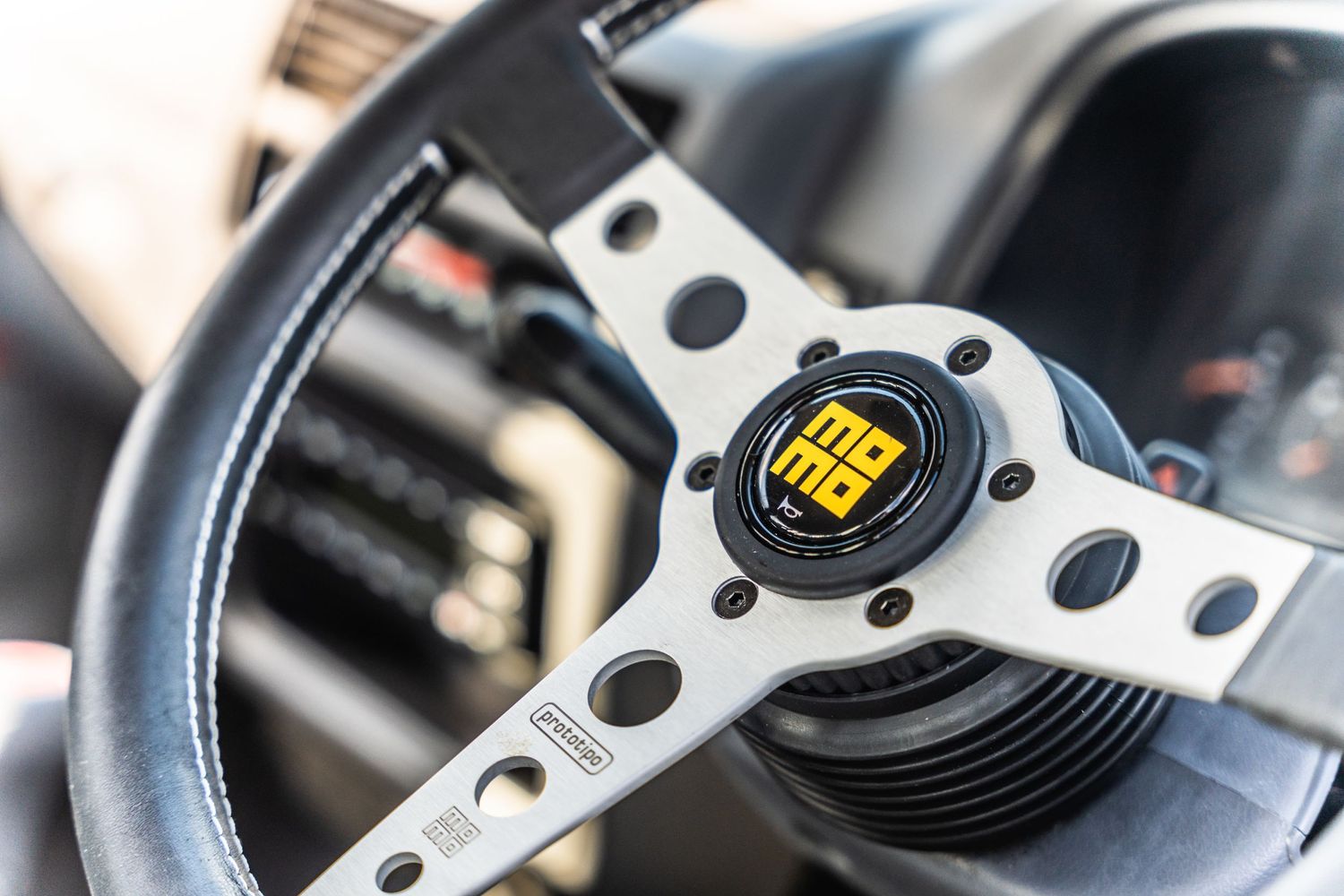 Close-up of a MOMO steering wheel center with perforated metal design.