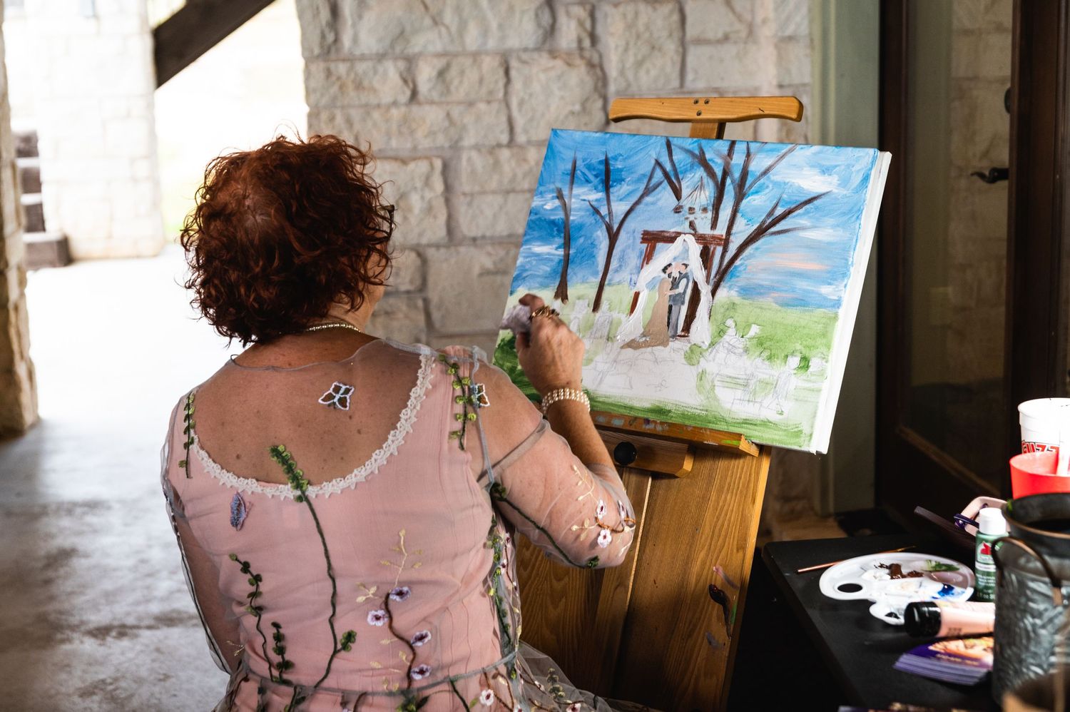 Artist painting winter landscape scene on canvas in stone corridor.