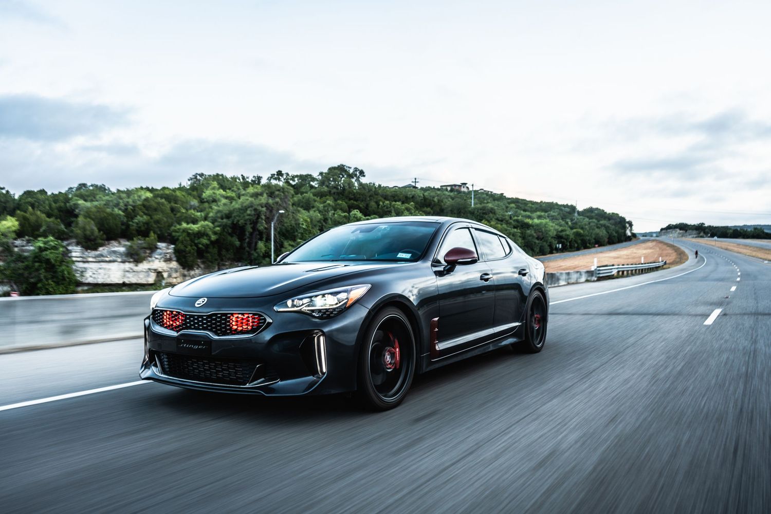 Modified Kia Stinger GT with black wheels photographed during dynamic driving.